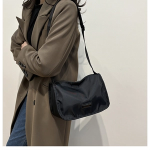 Close-up of black nylon crossbody bag with wide adjustable strap on a female model