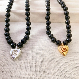Collier de perles onyx 7mm avec pendentifs coeurs tourbillon en finition dorée et argentée