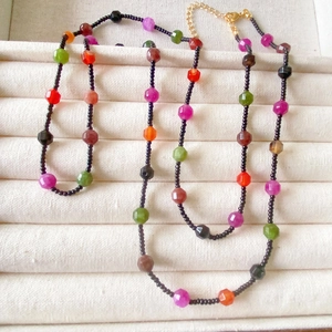 Colorful natural stone beaded necklace with faceted gems and gold clasp on a white tray