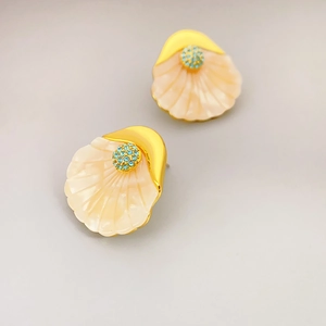 French shell-shaped gold earrings with turquoise rhinestones on gray background