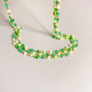Three-layer green and white cube beaded necklace with gold metal accents in S-curve layout
