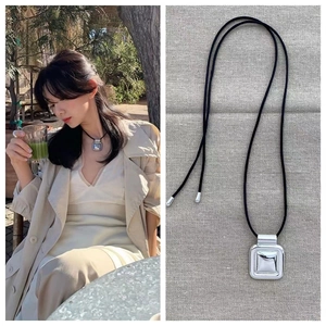 Collier à pendentif carré minimaliste avec cordon noir et vue sur modèle en extérieur
