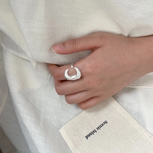Minimalist matte silver open moon ring with brushed texture on white fabric background