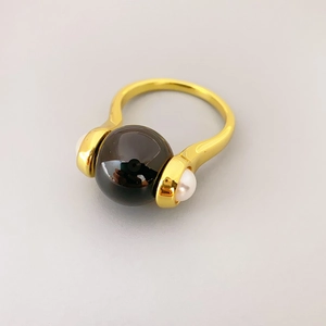 Detailed top view of a rotatable tiger eye stone ring with side pearl accents in gold plating