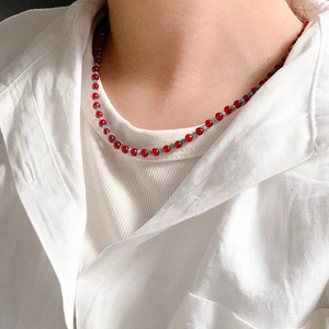 Collier minimaliste en perles d'agate rouge avec accents bleus sur chemise en lin