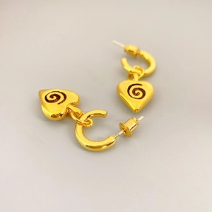 Dettaglio degli orecchini a cuore dorati con spirale in smalto nero e cerchi a forma di C