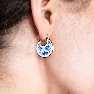 Close-up of blue and white enamel hoop earrings in 18K gold plated brass finish