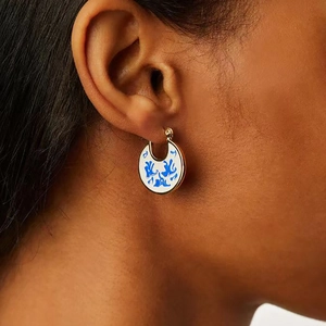 Detailed macro view of gold hoop earring with blue floral porcelain pattern