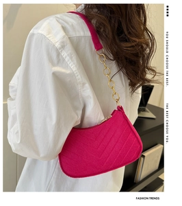 Detail of rose red felt underarm bag with V-shaped quilting and gold chain strap