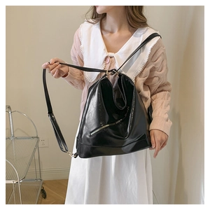 Close-up of shiny black PU leather tote bag with metallic zipper and adjustable strap
