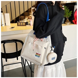 Detail of white canvas bucket bag with blue shoulder strap and pink drawstring closure