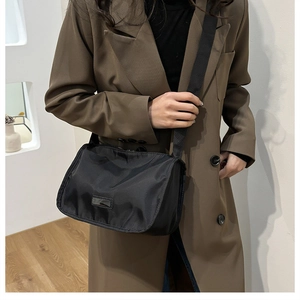 Close-up of black nylon crossbody bag with wide shoulder strap on professional model