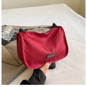 Macro detail of wine red nylon shoulder bag with black strap and silver zipper