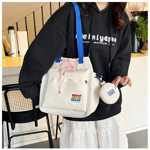 Detail of white canvas bucket bag with blue straps and colorful WAAII letter branding