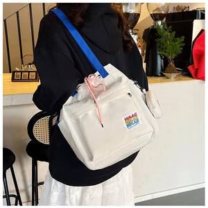 Detailed side view of white canvas bucket bag with colorful patches and mini round coin purse