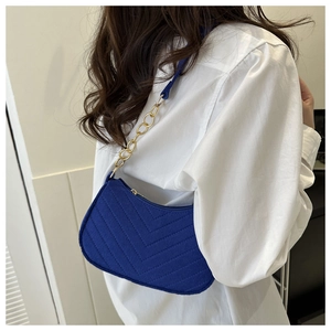 Detail of royal blue quilted shoulder bag with fine texture and gold chain strap