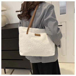 Dettaglio della texture in peluche bianco e dei manici in pelle marrone della borsa