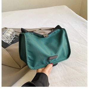 Close-up of dark green nylon pillow bag with black handle and silver zipper detail