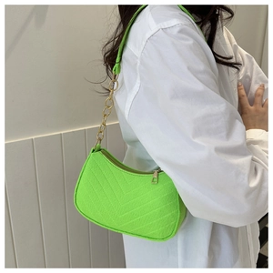 Detailed texture of neon green shoulder bag with chevron stitching and gold chain