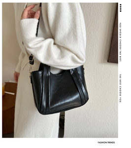 Close-up of black leather bucket bag with gold hardware worn by model on shoulder