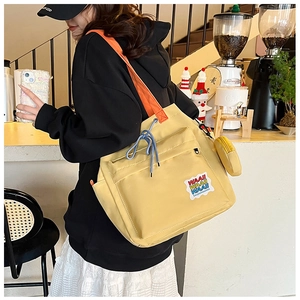Detail of yellow nylon tote bag with orange straps and mini coin purse attachment