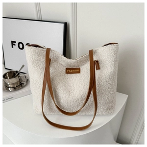 Dettaglio della borsa tote in peluche bianco con manici in pelle marrone e logo patch