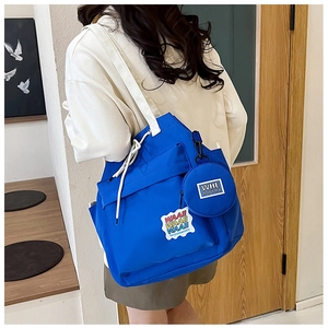 Detail of royal blue canvas bucket tote featuring print patch and small round coin purse pouch