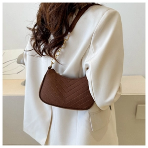 Detail of coffee-colored corduroy bag with V-shaped quilting and gold chain strap