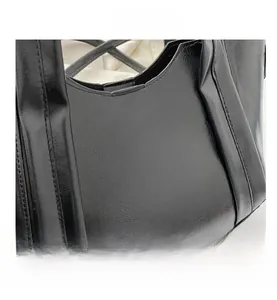 Macro detail of the black faux leather tote with textured finish and reinforced stitching