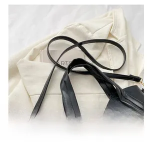 Detail of glossy black PU leather tote with gold hardware and adjustable shoulder strap