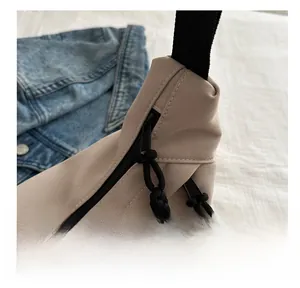 Detail view of khaki crossbody bag showing dual zippers with black woven pull cords