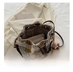 Detail view of the plush bucket bag capacity with a cute teddy bear charm and leather strap