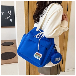 Blue canvas bucket bag with WAA letter patch and a round coin purse hanging on the side