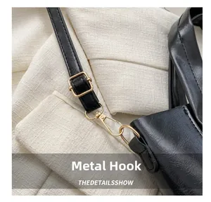 Detailed close-up of premium gold-plated metal hook on black leather shoulder bag