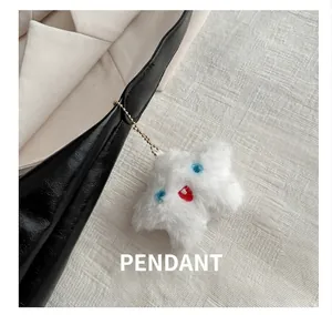 Close-up of a white plush star-shaped charm with a cute face on a black leather bag