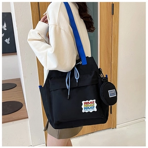 Black canvas bucket bag with blue straps and detachable coin purse on a female model