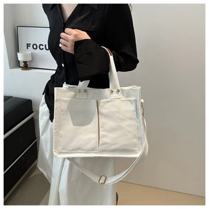 Détail du sac cabas minimaliste en toile crème avec poches et bandoulière réglable