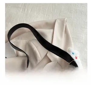 Detail of comfortable wide handle on a black leather tote bag with a plush charm