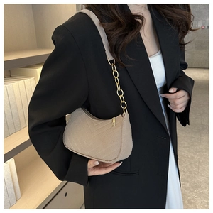 Detail of light beige felt underarm bag featuring V-shaped quilting and gold chain strap