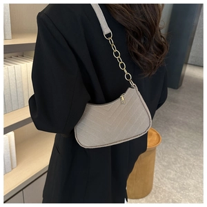 Detail of light gray quilted felt shoulder bag featuring a stylish golden chain strap