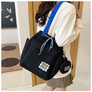 Detail of black canvas bucket bag with bright blue strap and drawstring closure