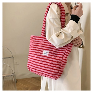 Dettaglio della borsa tote in morbido peluche a righe rosa e rosse con etichetta in tessuto