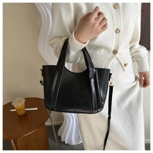 Minimalist black leather tote bag featuring gold hardware and removable shoulder strap