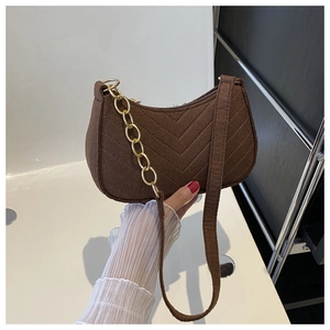 Detailed close-up of brown quilted felt underarm bag with golden chain strap and zip closure