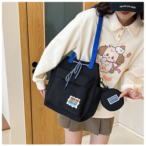 Detail of canvas shoulder bag with blue straps, colorful patches and mini coin purse
