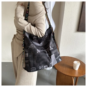 Black canvas shoulder bag with vintage newspaper print and colorful LOVE logo strap