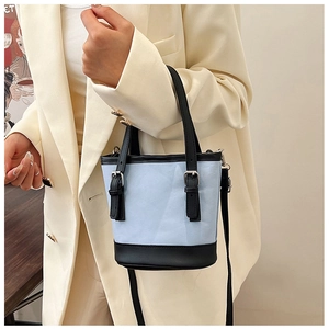 Detail of light blue crossbody bucket bag with black leather straps on a stylish model