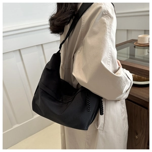 Detail of black nylon tote bag with braided zipper pull shown in lifestyle setting