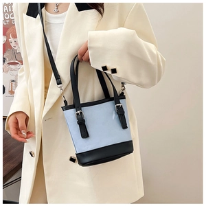 Detailed view of color-block bucket bag with adjustable buckles and silver hardware