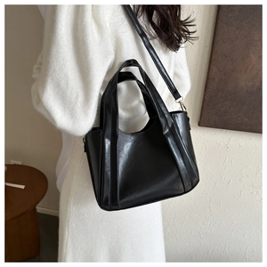 Detail of matte black leather tote bag with gold hardware and wide shoulder straps